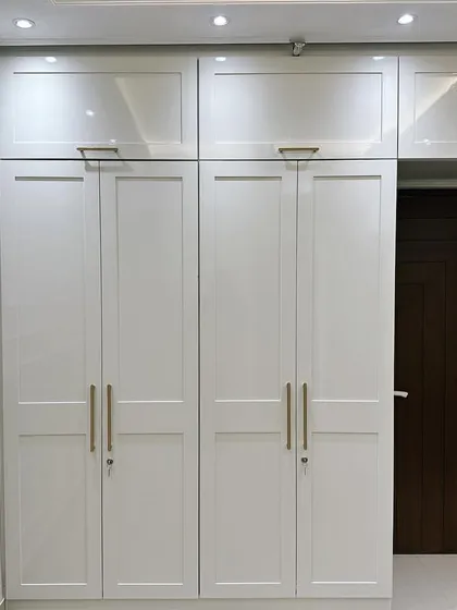 A beautiful example of a wardrobe that blends modern and Victorian design elements. The clean lines of the white shaker-style doors are complemented by elegant gold handles and classic wall moulding, creating a storage solution that is both highly functional and visually stunning.