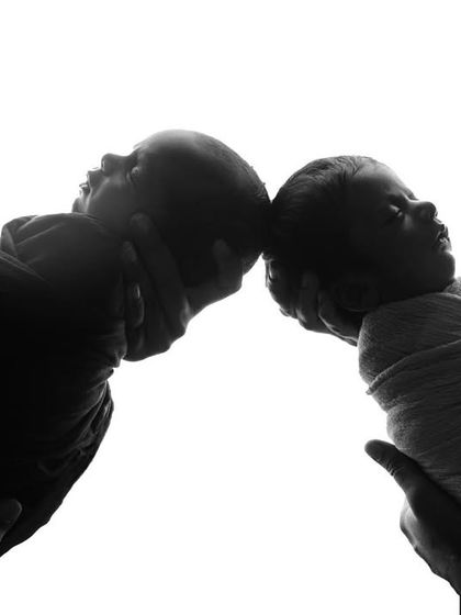 A creative silhouette shot of newborn twins being held up, their profiles creating a beautiful and artistic image.