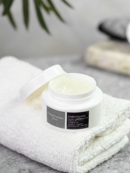An under-eye gel is shown open on a clean white towel. This minimalist setup highlights the product's clear, refreshing texture and suggests a spa-like, self-care moment.