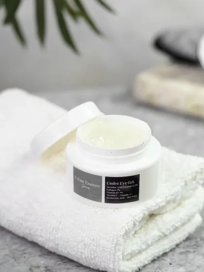 An under-eye gel is shown open on a clean white towel. This minimalist setup highlights the product's clear, refreshing texture and suggests a spa-like, self-care moment.
