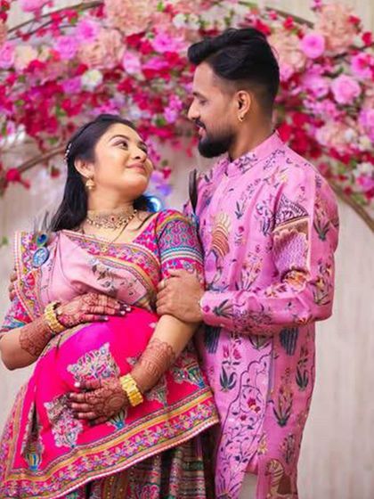The joy of the occasion is clear in this photo. The couple's matching pink attire adds to the festive and loving atmosphere of their baby shower celebration.