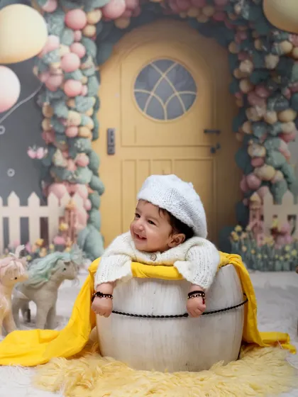 A joyful moment in a whimsical dollhouse world. This happy baby peeks out of a barrel prop, set against our colorful and imaginative fairytale backdrop.