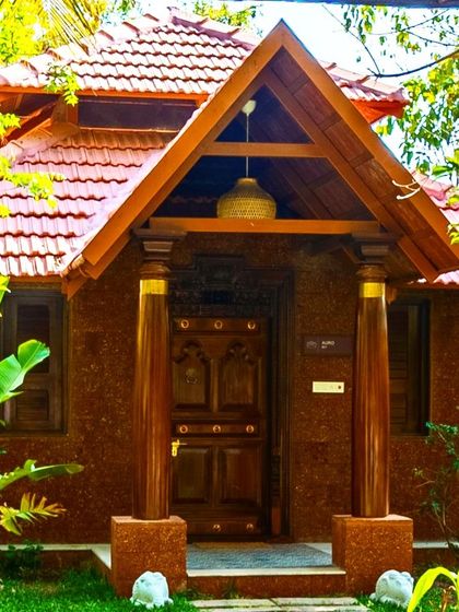 A closer view of the entrance to the Brown Town Resort cottage. The design features a traditional gabled roof with terracotta tiles and sturdy wooden pillars, creating an authentic, earthy feel.