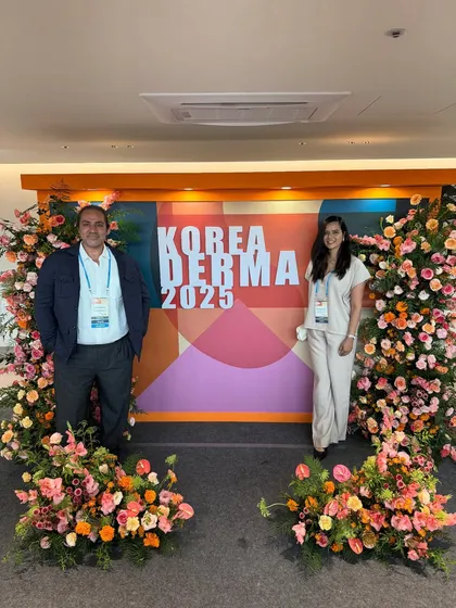 Standing with my husband in front of the floral display at Korea Derma 2025. It's wonderful to share these professional milestones with family.