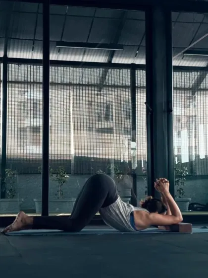 The dark, focused aesthetic of Lift Studios creates the perfect atmosphere for deep work. This student is practicing a preparatory pose for an inversion, using blocks to support her shoulders and build strength.