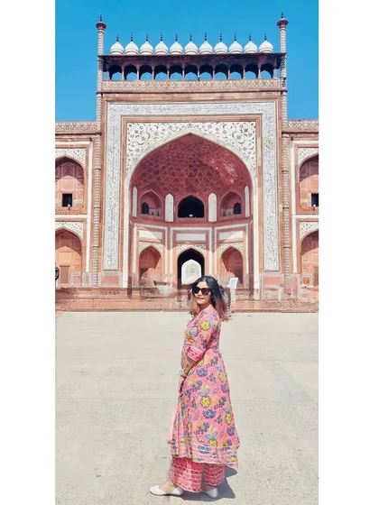A panoramic-style shot of me at the entrance of the Taj Mahal, capturing the grand scale of the architecture.
