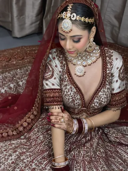 A graceful pose showing the bride looking down at her arm, highlighting the delicate details of her lehenga, bangles, and henna.