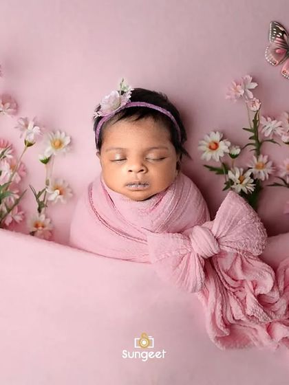 Pretty in pink. This newborn girl is swaddled in a soft pink wrap, surrounded by delicate flowers and butterflies, creating a sweet and serene garden-themed portrait.