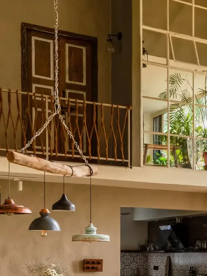 A custom light fixture made from a simple wooden log and mismatched pendants hangs above the dining area. This upcycled element, paired with the jute railing in the background, showcases our commitment to creative, zero-waste design.