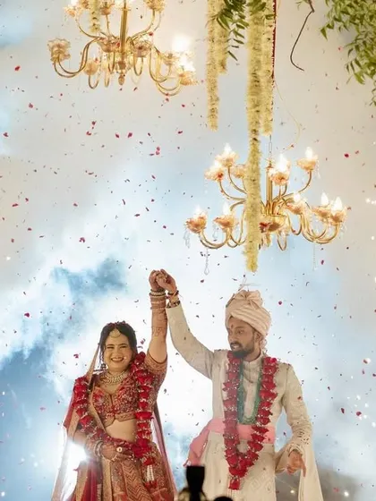 A joyous Varmala moment, with the couple celebrating under a canopy of chandeliers and a shower of cold pyro sparks.