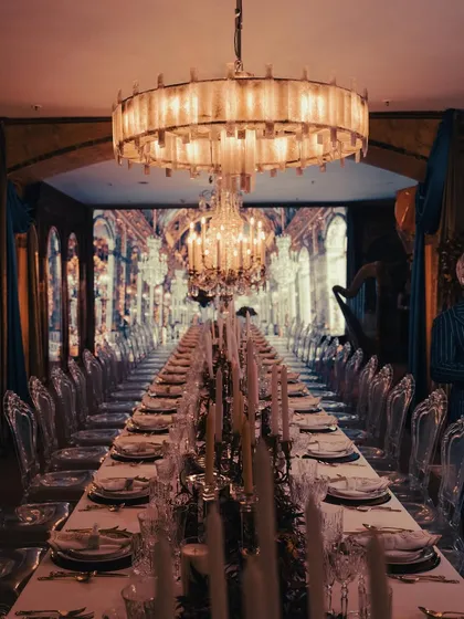A breathtaking view of our tablescape for an event inspired by the Château de Versailles' Hall of Mirrors. The endless table, dramatic chandeliers, and warm candlelight created an opulent and truly immersive dining atmosphere.