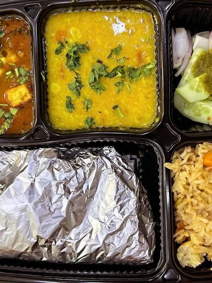 A colorful thali with matar paneer, yellow dal, and a vegetable pulao. A complete and delicious meal that is also visually appealing.