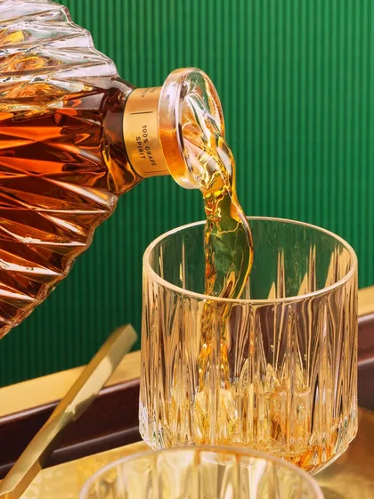 A close-up of the Monarch pour, focusing on the liquid hitting the crystal glass. You can see the texture of the glass and the motion of the brandy, creating a dynamic and appetizing image.
