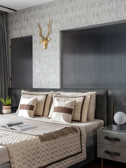 This all-monochrome master bedroom is a symphony of textures. A grey leather bed, cherry wood flooring, and a fluted glass partition create a space that is warm, cozy, and incredibly inviting.