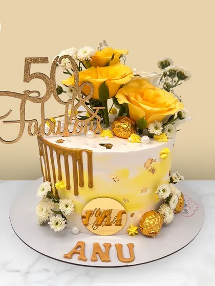 "50 & Fabulous." A sunny yellow and gold drip cake for Anu's 50th birthday, adorned with fresh yellow roses and Ferrero Rocher chocolates.