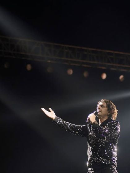 A classic shot of Sonu Nigam, the maestro, addressing the audience. The single spotlight from above creates a dramatic, almost divine effect, highlighting his legendary status.