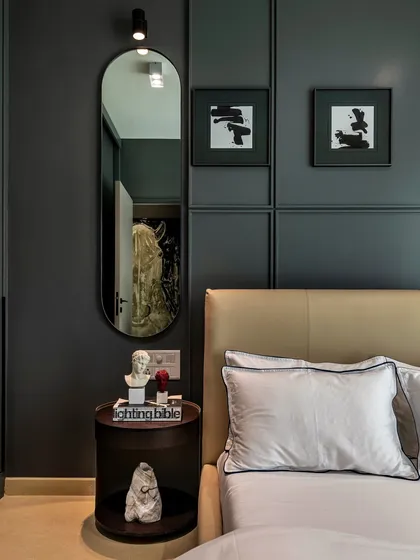 A close-up of the bedside in the dark-toned bedroom. The composition of the oval mirror, abstract art, and sculptural objects demonstrates my belief in curating every detail to contribute to the overall narrative of the space.
