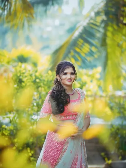 Using foliage in the foreground to create a sense of depth and intimacy. This technique draws the viewer's eye directly to the subject's smiling face.