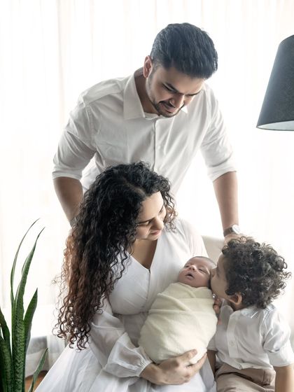 The strongest bond. A family of four, with a big brother giving his new sibling a gentle kiss.