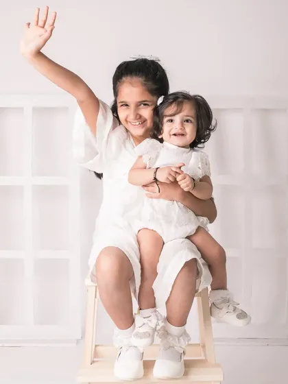 A happy wave from the big sister! This portrait is full of life and captures the fun and energy of sisterhood.