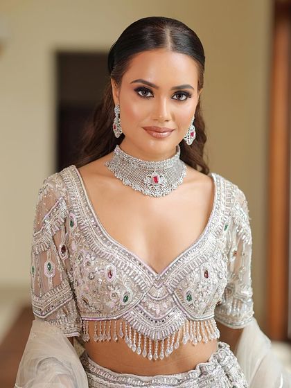 A stunning portrait of the model in a silver lehenga. The makeup is bold yet elegant, with strong eyes and a perfectly contoured base.