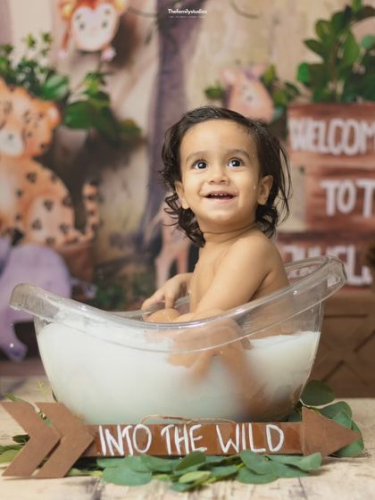 A happy baby boy looks up with a huge smile during his 'Into the Wild' milk bath photoshoot.