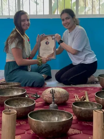 A student is awarded her certificate after completing both Aerial Yoga and Sound Healing courses, showcasing her diverse skills.