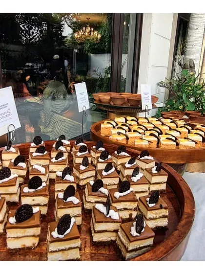 A wooden platter filled with rows of delicate tiramisu or layered coffee cake squares. This classic Italian dessert is a sophisticated and crowd pleasing addition to our high tea and dessert menus.