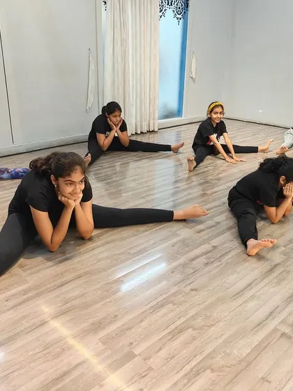 A moment of rest and stretching during a dance class. We ensure our spaces are comfortable for both intense practice and cool-down periods.