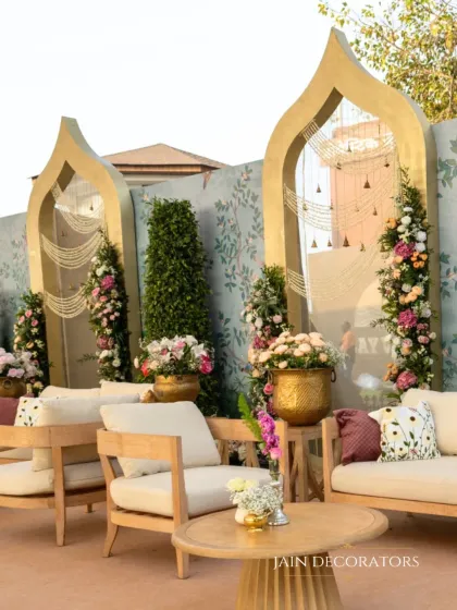 A comfortable and stylish lounge area for guests. The light wood furniture is paired with cushions and floral arrangements that match the pastel theme of the wedding.