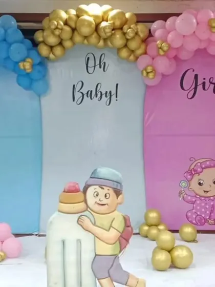 A simple and fun gender reveal backdrop. The "Oh Baby, Boy or Girl" theme is brought to life with blue and pink panels, character cutouts, and matching balloon arches.