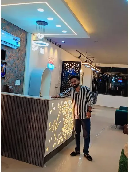 Standing at the custom-designed reception desk for our Faridabad salon project. The desk features a backlit logo and fluted panel details, creating a strong first impression the moment a client walks in.