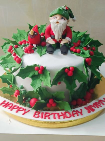 A festive birthday cake with a Christmas theme. This design features a fondant gnome and holly leaves, perfect for a December baby.