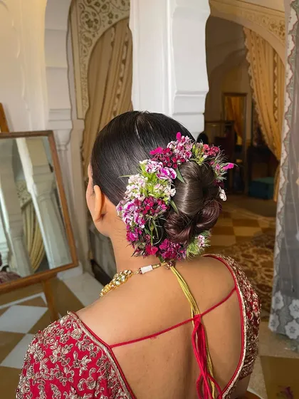 A side view of an intricate floral bridal bun. Notice how the flowers are woven into the hair to create a seamless, garden-like effect.
