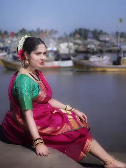 The bride-to-be posing by the water, her traditional saree and makeup creating a stunning contrast with the rustic background.