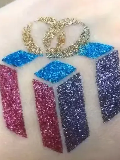 A multi-colored glitter tattoo of a Christmas gift. This is a fun and creative design that captures the excitement of the holiday season.