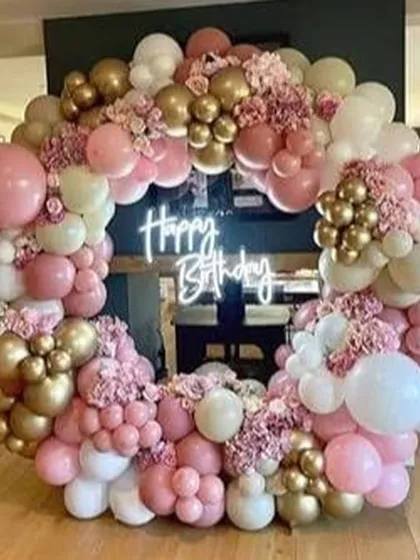 This stunning full-ring balloon display is perfect for a sophisticated party. The arrangement uses shades of pink, cream, and gold, with floral accents and a central neon sign.