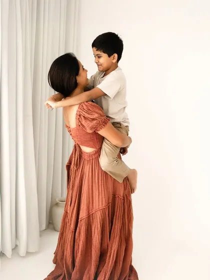 A mother effortlessly holds her son, both sharing a loving look. This portrait showcases the strength and tenderness of a mother's love.