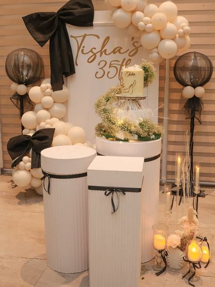 The complete cake and dessert station for a 35th birthday. We used white plinths of varying heights, a custom backdrop with the birthday girl's name, and elegant balloon and floral decor to create a stunning focal point.