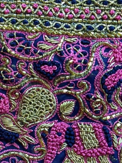A macro shot of the intricate embroidery, highlighting the different stitches and textures used to create the peacock and floral patterns.