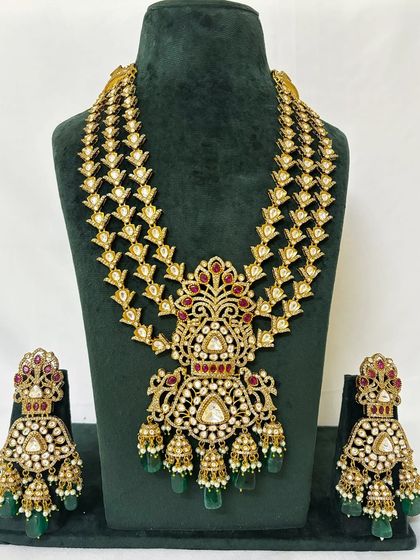 This grand bridal rental set features a multi-layered Rani Haar with a large, ornate pendant. The matching choker and jhumka earrings complete this stunning wedding look.