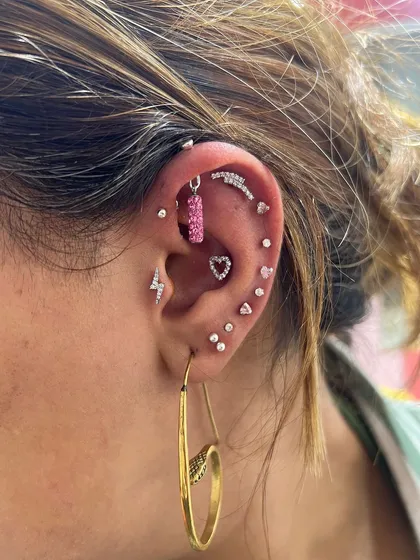This ear stack is full of fun and personality, featuring a pink bar hanging, lightning bolt studs, and multiple heart-shaped pieces.
