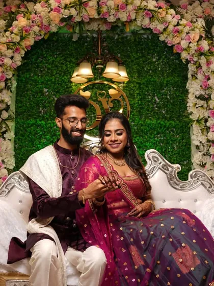 A lovely portrait of a newly engaged couple seated against a lush green and floral backdrop.