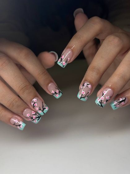 A beautiful cherry blossom nail art design. This set features a mint green French tip with hand-painted cherry blossom branches on a sheer nude base.