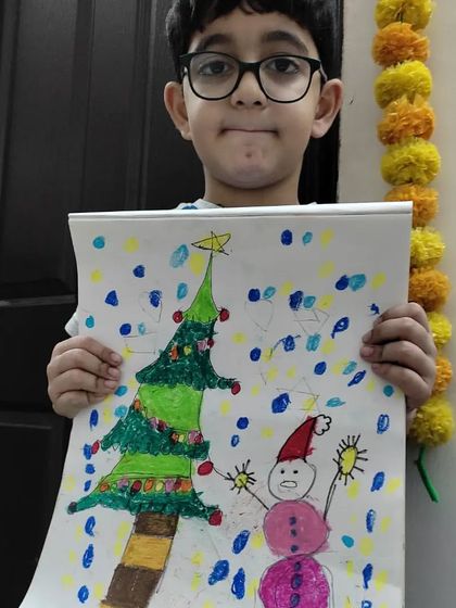 A young artist proudly displays his cheerful Christmas drawing, complete with a snowman and a decorated tree. This piece is full of personality and festive spirit.