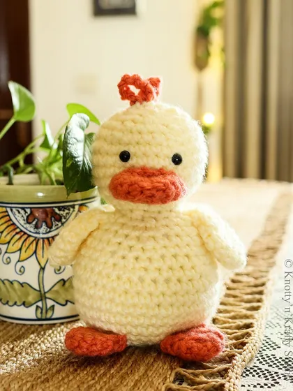 Here is another look at Lucky Ducky, a plump and cheerful crochet toy. His bright orange beak and feet add a fun pop of color, making him a delightful companion for any child.