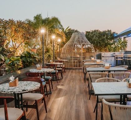 The rooftop terrace offers an open-air dining experience with stunning views. I used terrazzo tables, wooden chairs, and large, nest-like rattan seating pods, all surrounded by lush landscaping and ambient street-style lamps.