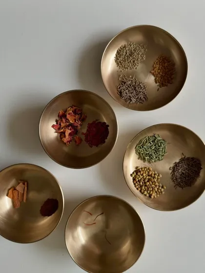 The heart of my work is pure, plant-based ingredients. This collection of medicinal herbs and spices in traditional brass bowls, including rose petals, sappanwood, and saffron, represents the natural palette I use to create my colors.