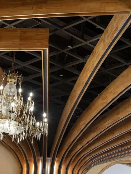 The ceiling at Nishtara is a key design feature. The exposed metal grid, required for plug-and-play lighting and decor, is artfully integrated with the curved wooden beams and a classic crystal chandelier, blending function and aesthetics.