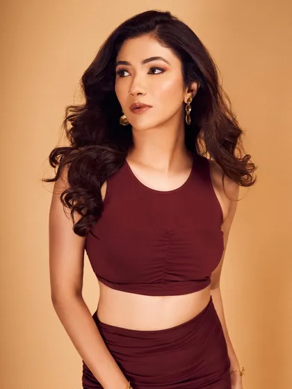 A chic and modern co-ord set. The makeup is warm and bronzy, with a defined eye and a glossy lip that completes this stylish look.